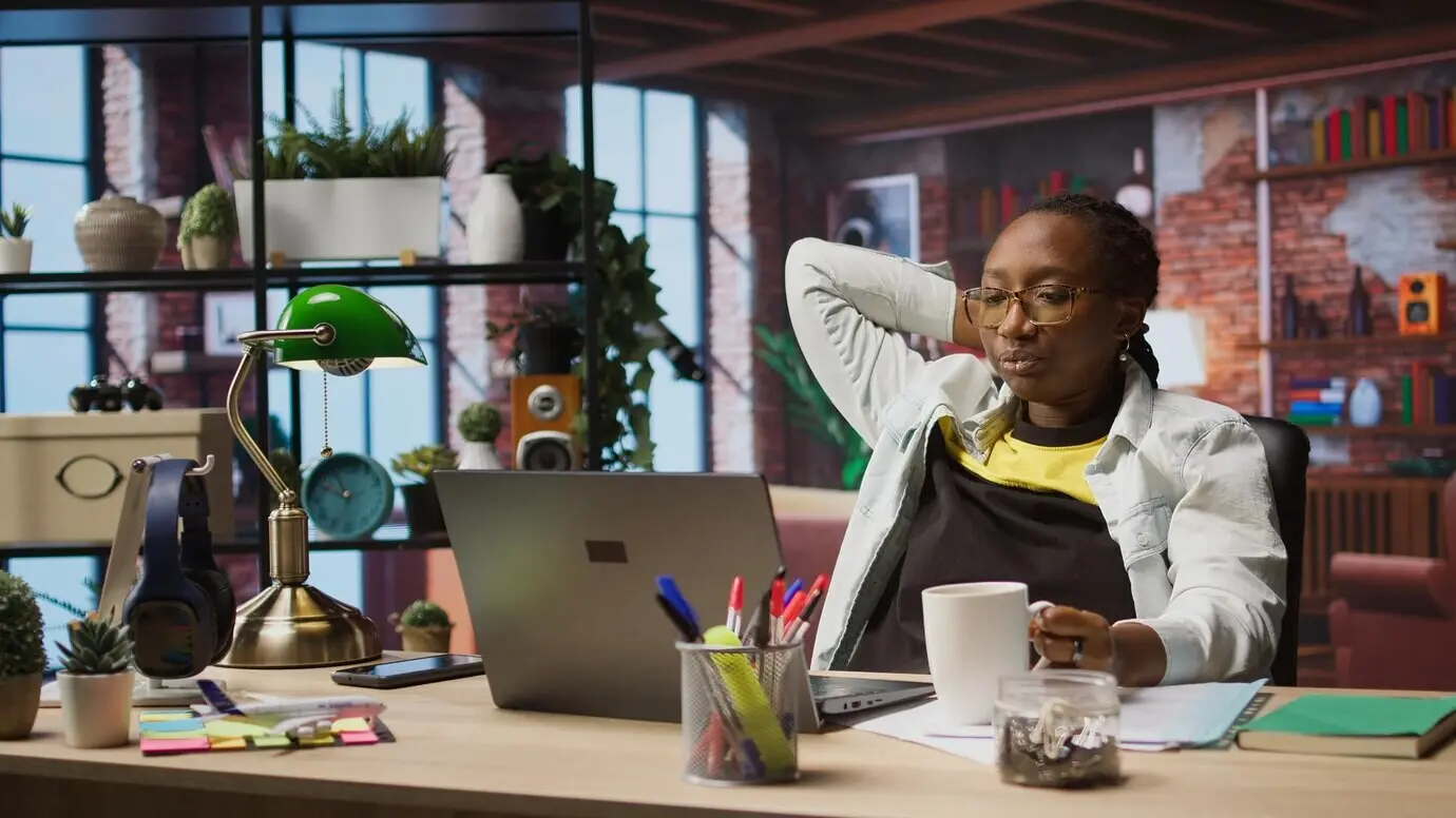 Eine Frau schaut sich zu Hause Filme auf dem Laptop an und trinkt dabei Kaffee.